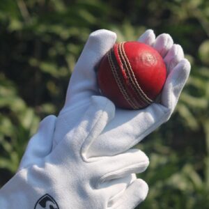 free photo of cricket ball held in gloves outdoors
